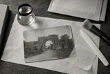 A photograph restoration desk with a magnifying loupe and archival tools — AI-generated editorial image