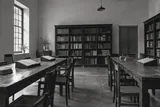 An empty reading room with wooden tables and shelves of reference books — AI-generated editorial image
